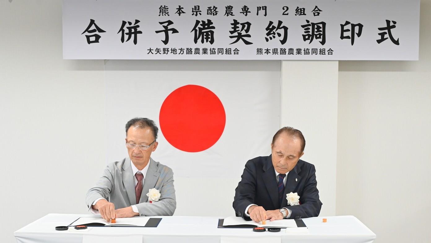 予備調印に臨む熊本県酪農協の山本健二組合長（右）と大矢野地方酪農協の水野幸也組合長